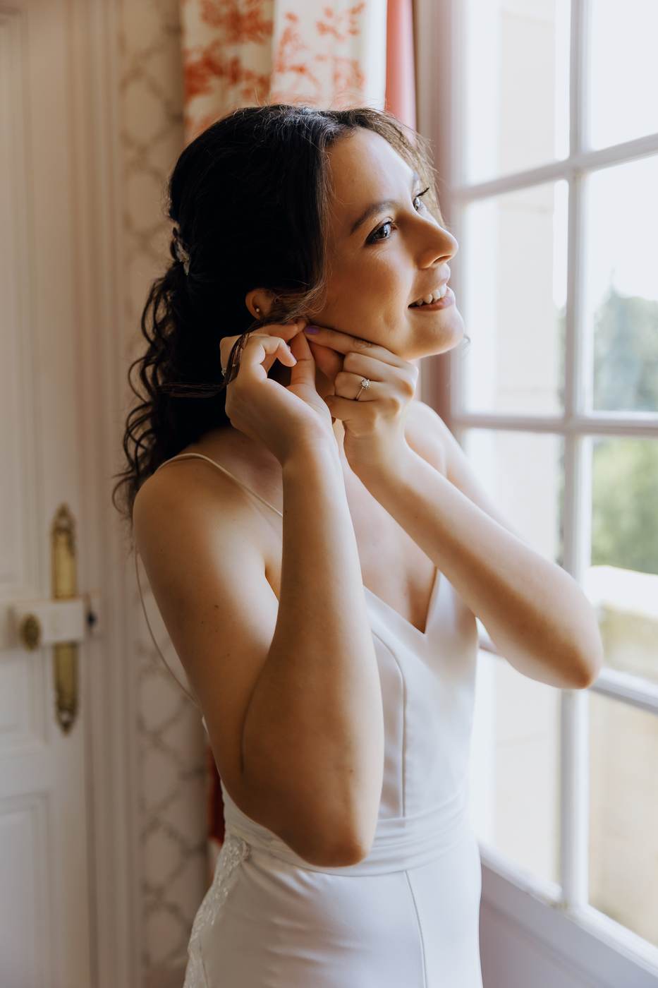 Laura met ses boucles d’oreilles dans la lumière de la fenêtre