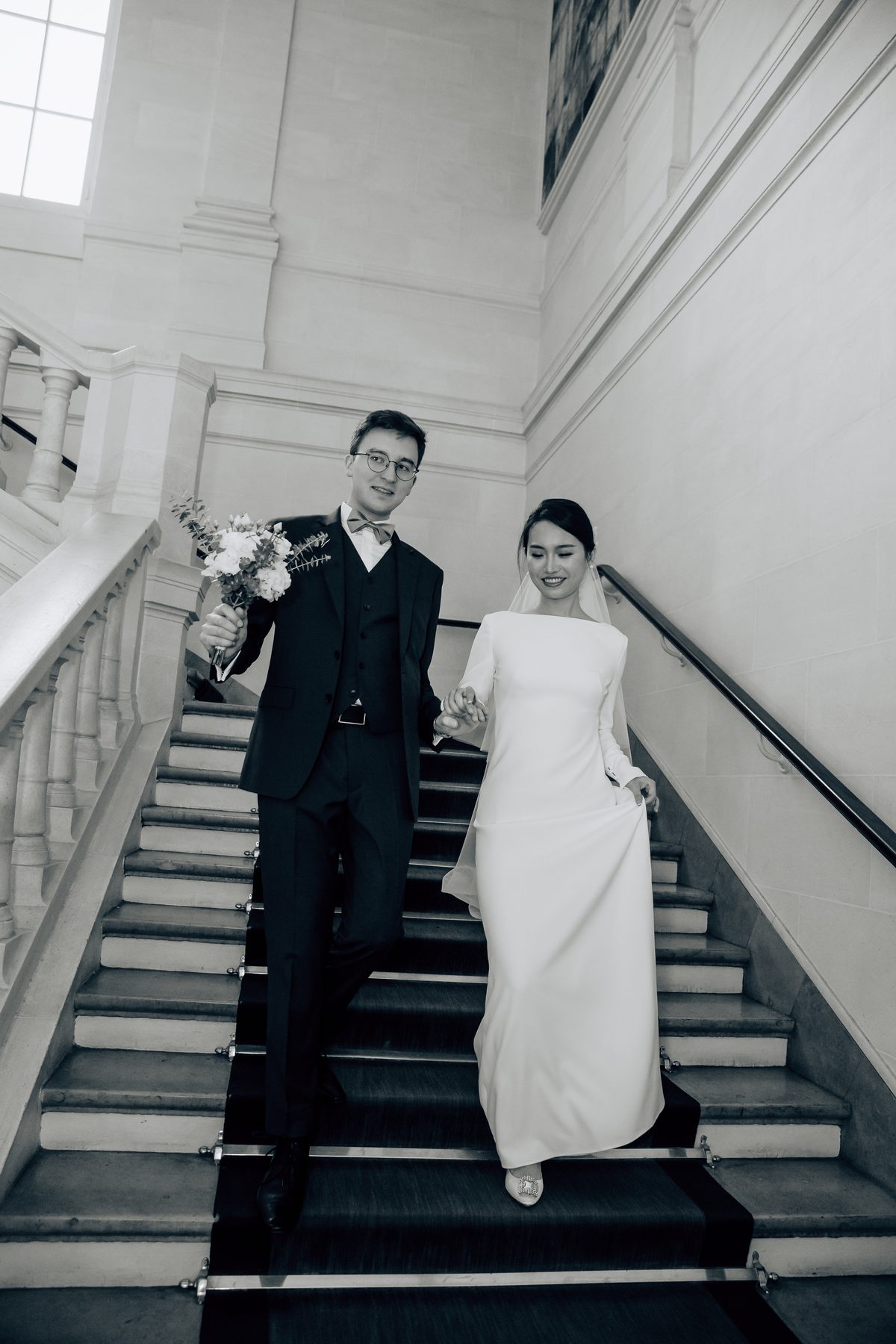 Les mariés descendent le grand escalier de la mairie en noir et blanc