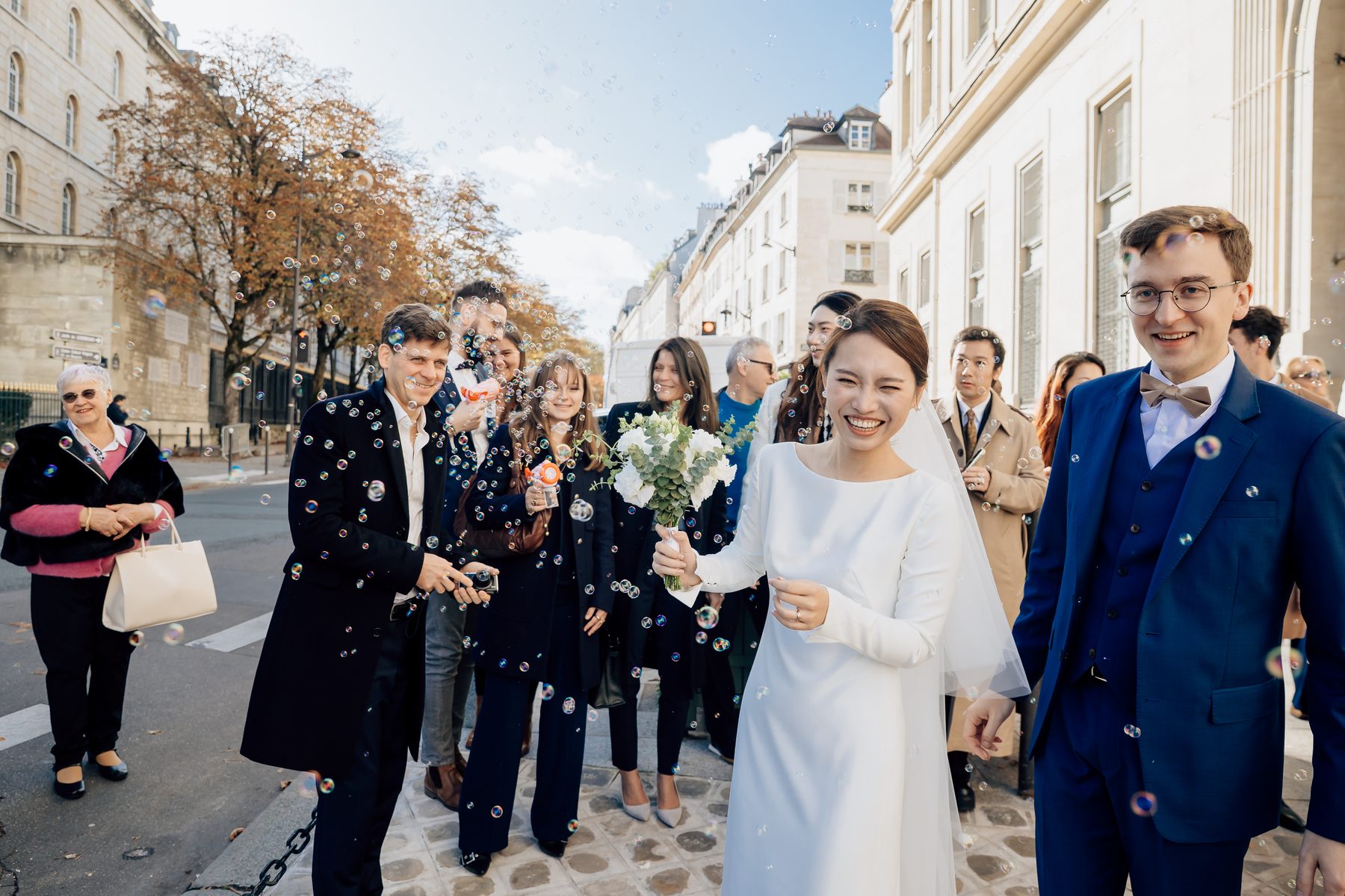 La mariée sourit au milieu des invités et des confettis