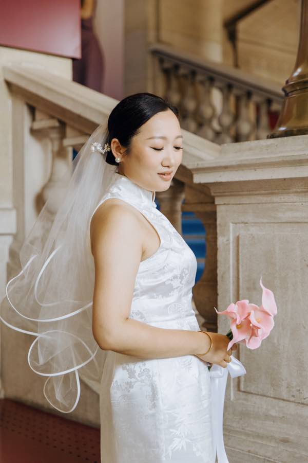 Jing en robe de mariage chinoise blanche dans l’escalier de la mairie