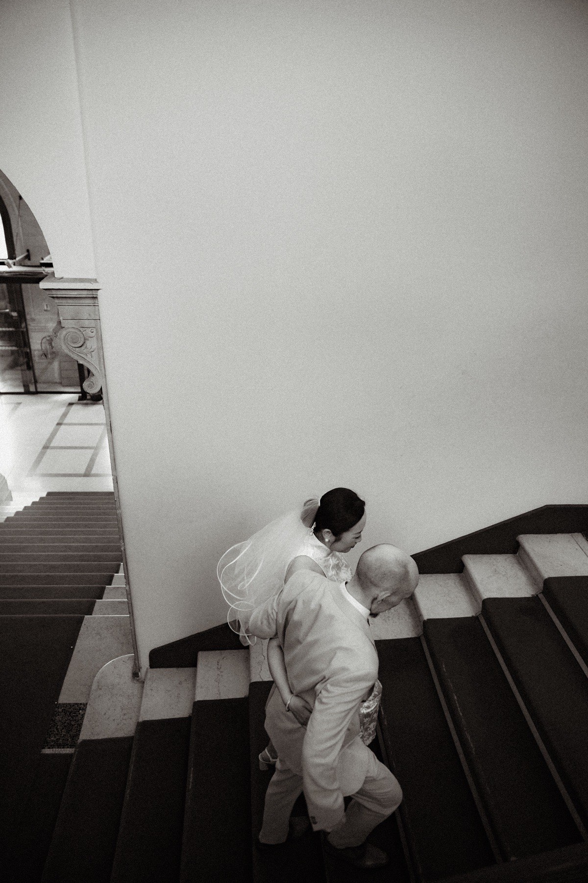 Mariés descendant un escalier intérieur dans une photographie en noir et blanc