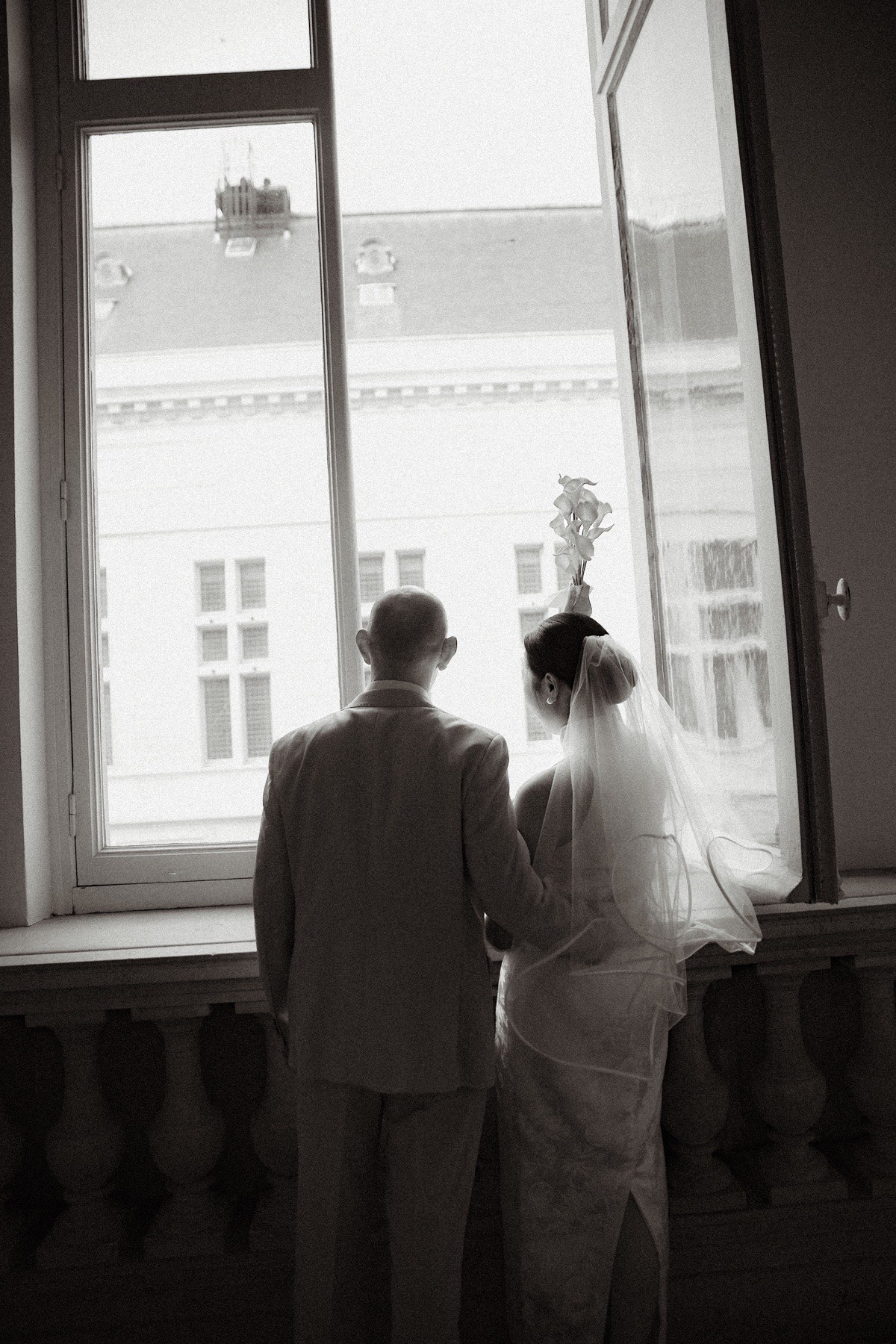 Mariés devant une grande fenêtre de mairie dans une photographie en noir et blanc